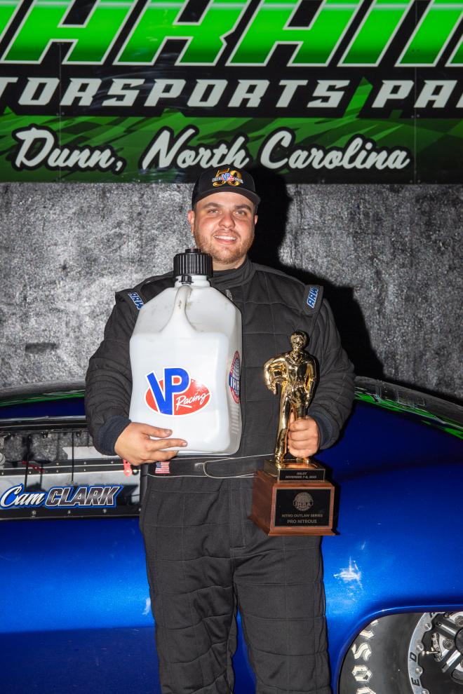 IHRA Pro Nitrous winner Cam Clark stands in the winner's circle at Darana Motorsports Park - Dunn with his Ironman trophy.